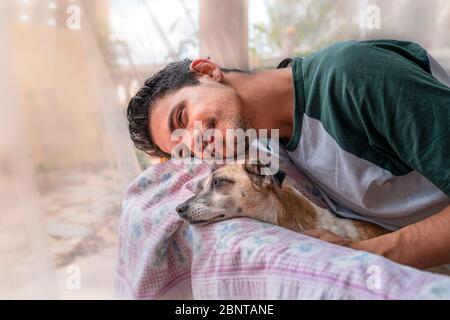 giovane e cane domestico, appoggiano la testa sulla schiena di una sedia nel giardino e sorridi. Foto Stock