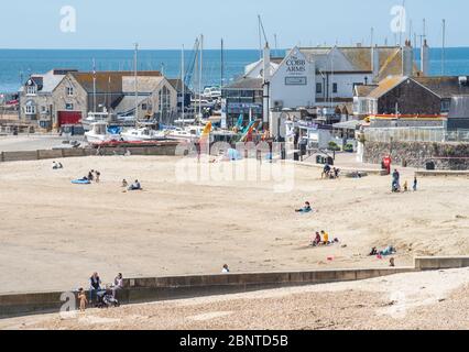 Lyme Regis, Dorset, Regno Unito. 16 maggio 2020. Regno Unito Meteo: La gente comincia a tornare alla spiaggia di Lyme Regis il primo Sabato soleggiato da quando le restrizioni del governo coronavirus sono stati attenuati. I visitatori provenienti da fuori Dorset sono invitati a 'stare lontano e visitare più tardi', come il consiglio ha gestito parcheggi e bagni pubblici presso le spiagge popolari e luoghi di bellezza in tutta la contea rimanere chiuso per scoraggiare le persone provenienti da fuori della regione di visitare su ciò che è impostato per essere un caldo e weekend soleggiato. Credit: Celia McMahon/Alamy Live News Foto Stock