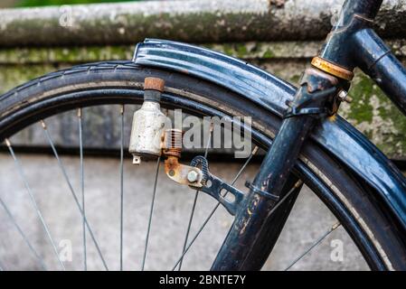 Dinamo di una vecchia bici d'epoca arrugginita parcheggiata in una strada ad Amsterdam, Paesi Bassi Foto Stock