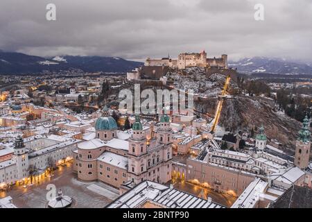 Panoramica dei droni aerei della cupola di Salisburgo ricoperta di neve ai piedi della fortezza di Hohensalzburg al tramonto in inverno Foto Stock