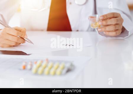 Donna-medico sconosciuto riempie in su la forma di prescrizione in stanza soleggiata, primo piano Foto Stock