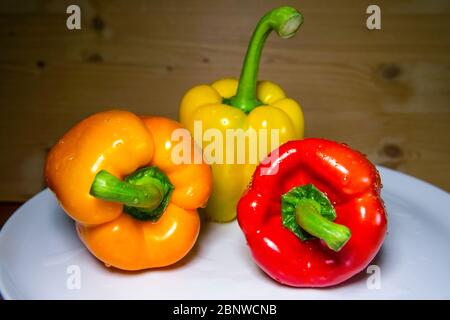 tre campanellini in diversi colori su piatto con fondo in legno Foto Stock