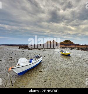 Immagine di piccole barche da pesca asciugate sulla spiaggia con rocce di sabbia e cielo nuvoloso. Le Hocq, St Clement, Isole del canale di Jersey Foto Stock