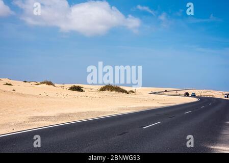 Autostrada FV-1 e dune di sabbia attraverso il parco nazionale a nord che conduce alla città di Coralejo, Fuerteventura, Isole Canarie. Foto Stock