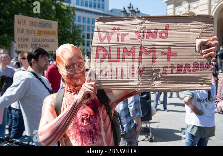 16 maggio 2020, Hessen, Francoforte sul meno: Con un cartello di cartone che dice 'Siamo stupidi e vogliamo morire', un contromessatore mescolato tra i partecipanti di un raduno davanti all'Alte Oper a Francoforte contro le misure di corona del governo. Foto: Boris Roessler/dpa Foto Stock