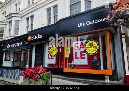 Llandudno, UK: 27 agosto 2019: Un negozio di abbigliamento e attrezzature per esterni neri con banner per finestre che pubblicizzano una vendita in cui tutte le scorte devono andare. Il stor Foto Stock