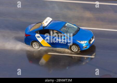 Auto blu passeggeri Yandex Taxi ride sulla pioggia bagnata spray autostrada vista aerea. Russia, San Pietroburgo. 15 maggio 2020 Foto Stock