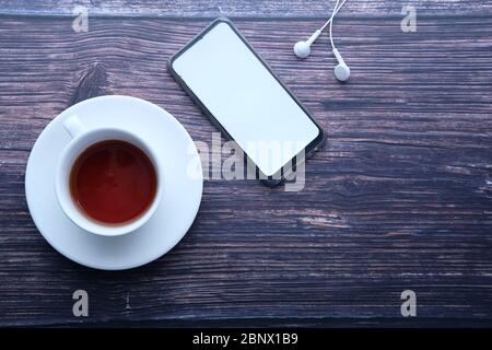 Vista dall'alto dello smartphone con schermo vuoto e blocco note su un tavolo in legno Foto Stock