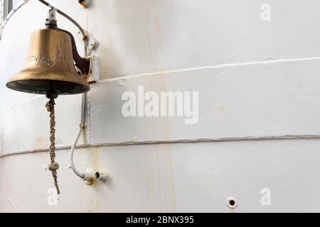 Campana di ottone all'esterno di una barca da caccia, metallo verniciato bianco, spazio copia, aspetto orizzontale Foto Stock