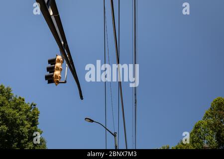 Braccio verticale con semaforo, linee elettriche e luce stradale contro il cielo blu con alberi sul bordo inferiore, aspetto orizzontale Foto Stock