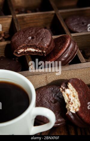 Spuntino dolce con caffè. Tazza bianca di caffè e torta Choco a metà consumata. Concentrati sulla torta Choco Foto Stock