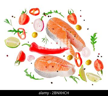 Bistecche grezze di pesce salmone che volano con verdure, spezie ed erbe isolate su sfondo bianco. Foto Stock