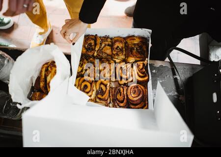 foto di una coppia che mangia da un contenitore di rotoli di cannella Foto Stock