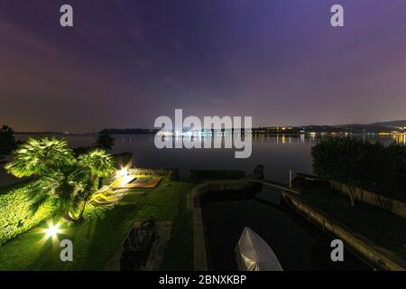 Vista sul Lago di Garda con le luci illuminate della città sull'altra sponda di notte Foto Stock