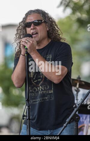 Cantante, in rock band, che si esibisce in un concerto all'aperto. Foto Stock