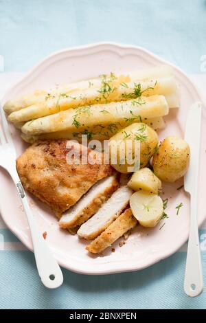 Costolette di maiale (schabowy) con patate da bambino e asparagi bianchi con aneto Foto Stock