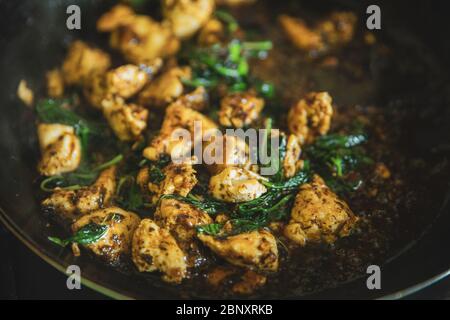 Scacchi di basilico tailandese in padella, tradizionale pasto fritto in padella, costolette di carne di pollo con frittura di foglie di basilico verde da vicino Foto Stock