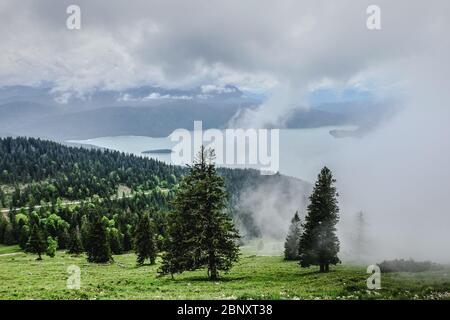 Vista su un lago di montagna in Baviera parzialmente coperto da nuvole Foto Stock