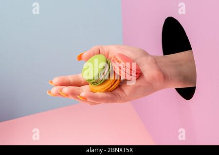 Primo piano sulla mano della donna che mostra macaron colorati Foto Stock