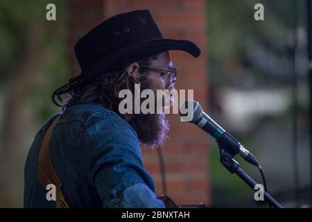 Cantante folk bearded che si esibisce in un concerto di outdoor. Cantare e suonare la chitarra acustica. Foto Stock
