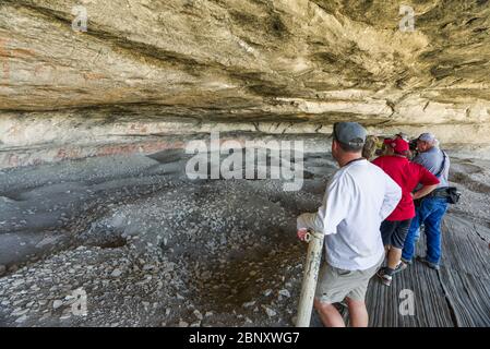 I turisti che guardano ai vari pittogrammi da parete Navajo al Fate Bell Shelter, all'interno del Seminole Canyon, Texas Foto Stock