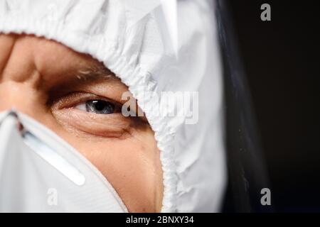 Serio medico in tuta protettiva e maschera ti guarda Foto Stock