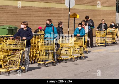 Montreal, CA - 16 Maggio 2020 : clienti in una linea fuori dal supermercato. Alcuni di essi indossano maschere di protezione Covid-19. Foto Stock