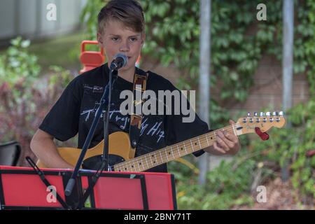 Giovane maschio che suona chitarra e canto in concerto all'aperto. Foto Stock