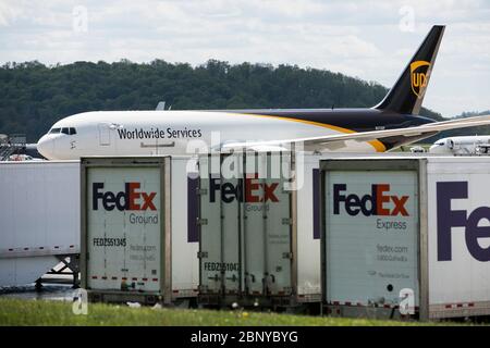 I rimorchi FedEx Express Truck sono visti di fronte a un aeromobile UPS Airlines United Parcel Service a Middletown, Pennsylvania, il 4 maggio 2020. Foto Stock