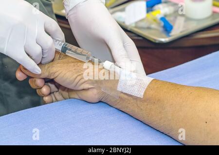 Siringa a pressione del medico nel tappo eparina mano del paziente Foto Stock