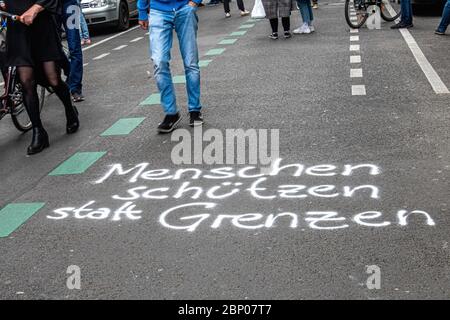 Mitte, Berlino, Germania. 16 maggio 2020 messaggio "Proteggi le persone istate di frontiere" in strada durante le demonestazioni durante la pandemia COVID-19. Molte opinioni sono state rappresentate alle proteste - estrema destra, estrema sinistra, teorici del complotto e vaxxers anti. I dimostranti dell'ala sinistra hanno espresso rabbia per il fatto che ai manifestanti dell'ala destra sia stata concessa un'area più ampia e prominente di fronte al teatro Volksbuhne. Le proteste di destra e di sinistra sono state contenute da un gran numero di agenti di polizia e sono stati effettuati diversi arresti. Foto Stock