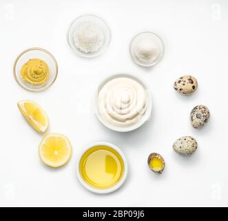 Ciotola con salsa maionese al centro e ingredienti maionese intorno ad essa isolati su sfondo bianco. Vista dall'alto. Foto Stock