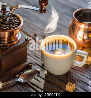Il caffè è ancora vivo. Tazza di caffè caldo e macinacaffè e cezve vecchio stile. Foto Stock