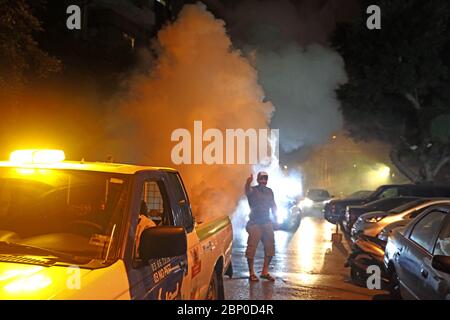 Beirut, Libano. 16 maggio 2020. Un gesto residente come un veicolo di controllo di peste spruzzi pesticidi per aiutare a combattere sciami di insetti a Beirut, capitale del Libano, 16 maggio 2020. Grandi sciami di insetti, compresi gli scarafaggi e le scarafaggi, hanno invaso all'inizio del venerdì mattina un certo numero di villaggi libanesi e campi per sfollati siriani nel Libano orientale. Gli sciami hanno raggiunto anche la capitale Beirut e altre città del sud, tra cui Sidon, la National News Agency ha riferito. Credit: Bilal Jawich/Xinhua/Alamy Live News Foto Stock