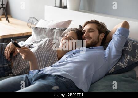 Giovane coppia che si stendeva a letto guardando la TV insieme Foto Stock