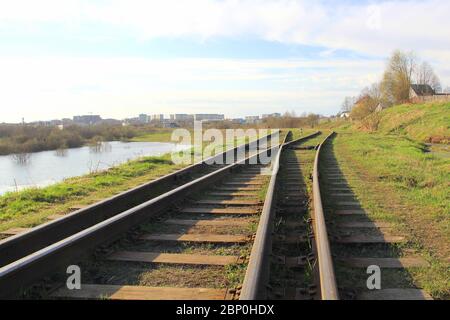 La ferrovia si estende in lontananza sullo sfondo di giovani verdi erba e alberi in primavera. Foto Stock