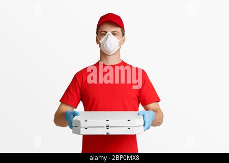 Autoisolamento a casa e consegna pizza durante la quarantena. Il deliveryman in maschera protettiva e guanti sono scatole di contenimento. Foto Stock