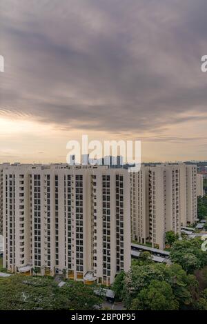 Nuvole spettacolari contro il cielo blu con edifici residenziali moderni e il paesaggio urbano in primo piano. Vista dalla finestra durante l'interruttore automatico SG Foto Stock