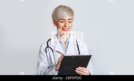 Il medico prescrive il farmaco. Donna sorridente in uniforme Foto Stock