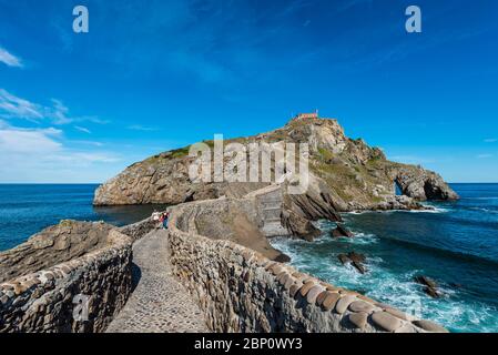 I turisti scendono i gradini per l'eremo sulla cima dell'isola di Gaztelugatxe Foto Stock