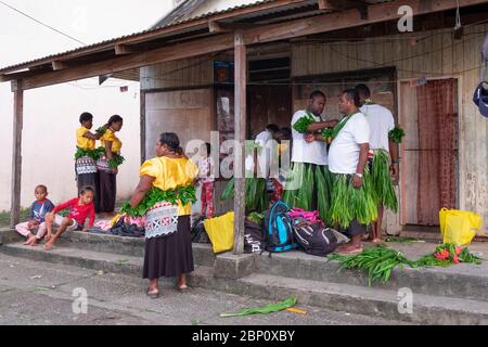 Uomini e donne si aiutano a vestire per una cerimonia tradizionale a Sigatoka (Singatoka), Figi. Foto Stock