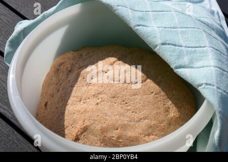 impasto di lievito in una ciotola coperta con un asciugamano su tavola di legno concetto di una cottura sana Foto Stock