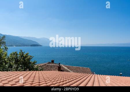 Bella vista del tetto tegole rosse, albero verde e lago Ohrid, Macedonia del Nord. Agosto 2019 Foto Stock