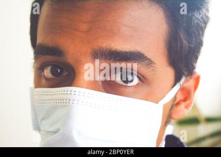 primo piano di un giovane uomo in maschera protettiva, rimani a casa e rimani al sicuro. Foto Stock