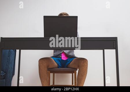 Uomo che indossa una giacca e un paio di shorts blu mentre lavora con il suo laptop. Foto Stock