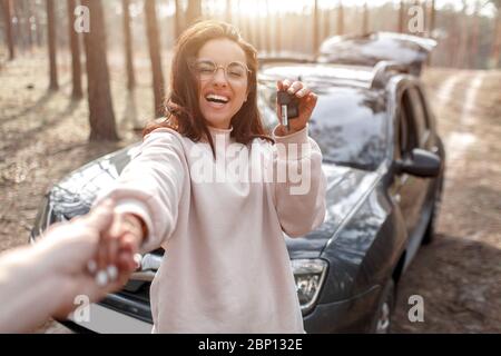 Viaggiare in auto. Bella auto donna dai capelli neri. Vacanze in campagna. Tiene le chiavi dell'auto nelle mani Foto Stock