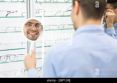 Buon uomo che sceglie gli occhiali al negozio di ottica Foto Stock