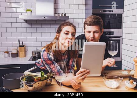 Giovane coppia allegra che prepara il cibo insieme a casa Foto Stock