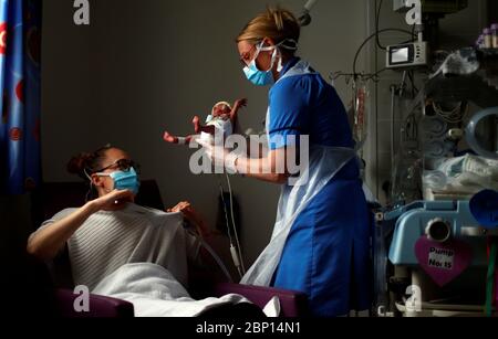 L'infermiera neonatale Kirsty Hartley porta il bambino prematuro Theo Anderson a sua madre Kirsty Anderson nell'unità di terapia intensiva neonatale presso il Lancashire Women and Newborn Center presso il Burnley General Hospital di East Lancashire durante lo scoppio della malattia del coronavirus. Foto Stock