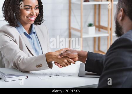 Responsabile di assunzione afroamericano scuotendo la mano di candidato di posto vacante durante il colloquio di lavoro in ufficio Foto Stock